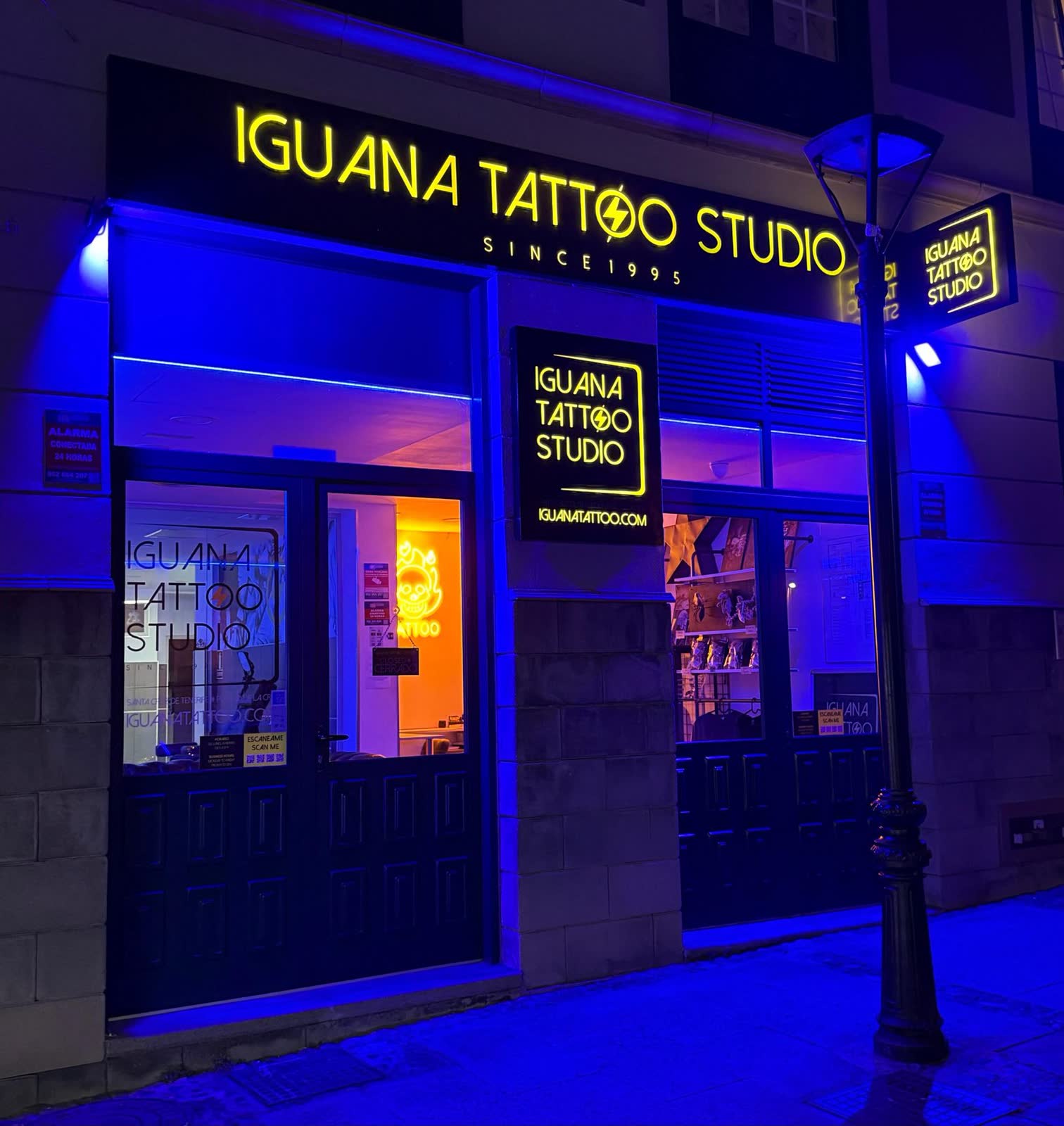 Fachada de Iguana Tattoo Studio de noche en la calle Agustín de Betancourt, Puerto de la Cruz, con el rótulo de neón encendido